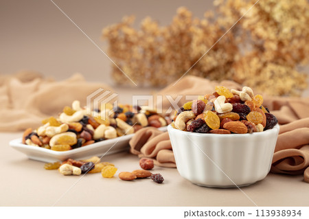 The mix of various nuts and raisins on a beige background. 113938934