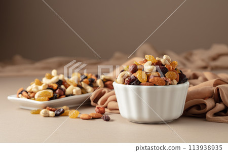 The mix of various nuts and raisins on a beige background. The mix of various nuts and raisins on a beige background. 113938935