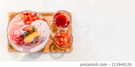 A dessert tray with a pink ice cream and strawberry toppings 113940126