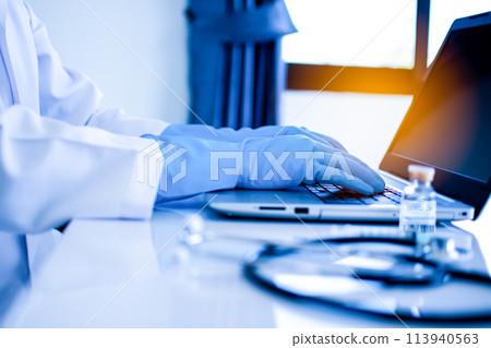A doctor is typing on a laptop computer in a medical setting A doctor is typing on a laptop computer in a medical setting 113940563