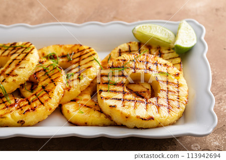 Grilled pineapple with lime honey glaze and whipped cream Grilled pineapple with lime honey glaze and whipped cream 113942694