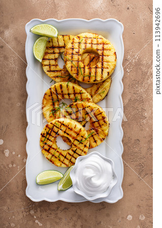Grilled pineapple with lime honey glaze and whipped cream Grilled pineapple with lime honey glaze and whipped cream 113942696