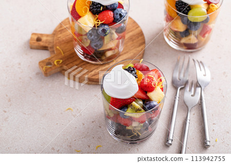 Fruit salad with berries and honey dressing served in a glass 113942755
