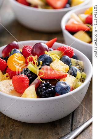 Fruit salad on a wooden table with berries and honey dressing 113943105