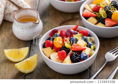 Fruit salad on a wooden table with berries and honey dressing Fruit salad on a wooden table with berries and honey dressing 113943106