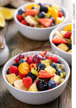 Fruit salad on a wooden table with berries and honey dressing Fruit salad on a wooden table with berries and honey dressing 113943107