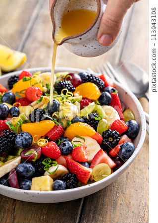 Fruit salad on a wooden table with berries and honey dressing 113943108