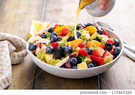 Fruit salad on a wooden table with berries and honey dressing 113943109