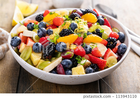 Fruit salad on a wooden table with berries and honey dressing 113943110