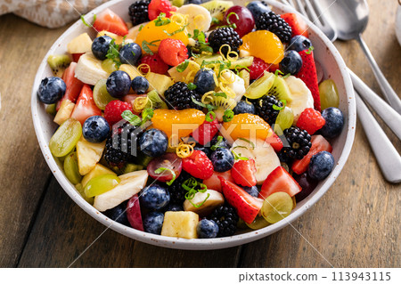 Fruit salad on a wooden table with berries and honey dressing Fruit salad on a wooden table with berries and honey dressing 113943115