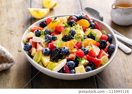 Fruit salad on a wooden table with berries and honey dressing Fruit salad on a wooden table with berries and honey dressing 113943116