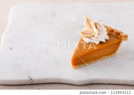 Slice of a traditional pumpkin pie for Thanksgiving topped with whipped cream 113943212