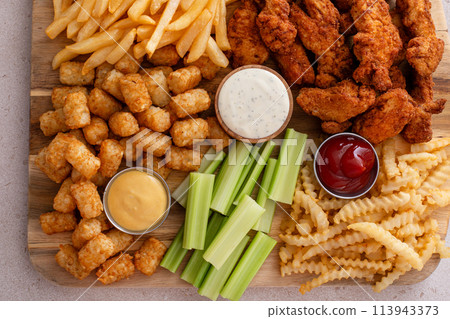 Fried chicken strips and french fries board with sauces and celery Fried chicken strips and french fries board with sauces and celery 113943373