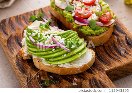 Avocado toasts with radishes, tomatoes and feta topped with olive oil Avocado toasts with radishes, tomatoes and feta topped with olive oil 113943395