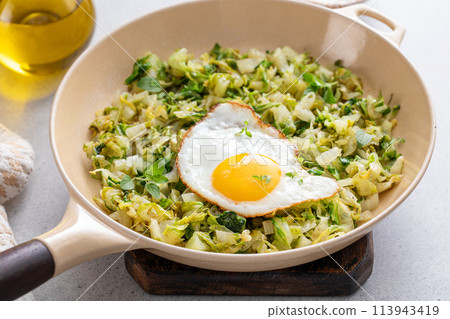 Sauteed cabbage topped with fried egg in a cast iron pan, vegetable lunch idea Sauteed cabbage topped with fried egg in a cast iron pan, vegetable lunch idea 113943419