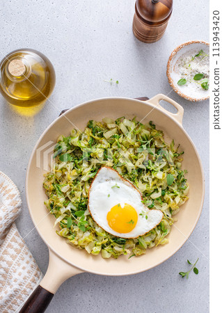 Sauteed cabbage topped with fried egg in a cast iron pan, vegetable lunch idea Sauteed cabbage topped with fried egg in a cast iron pan, vegetable lunch idea 113943420