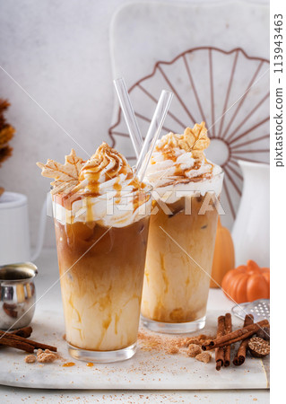 Iced pumpkin spice and caramel latte with whipped cream and syrup 113943463