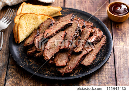 Sliced smoked brisket on a serving plate with toast Sliced smoked brisket on a serving plate with toast 113943480