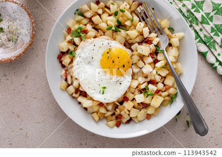 Potato hash with pancetta topped with a fried egg Potato hash with pancetta topped with a fried egg 113943542
