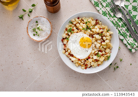 Potato hash with pancetta topped with a fried egg 113943543