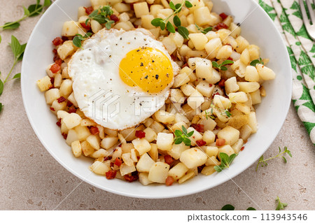 Potato hash with pancetta topped with a fried egg 113943546