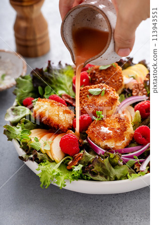 Fried goat cheese salad with apples and raspberries and vinaigrette dressing 113943551