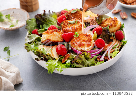 Fried goat cheese salad with apples and raspberries and vinaigrette dressing 113943552