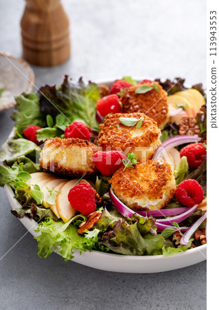 Fried goat cheese salad with apples and raspberries and vinaigrette dressing 113943553