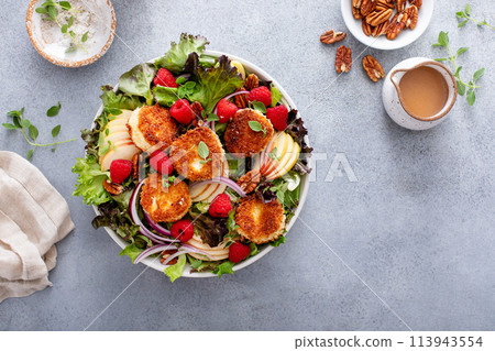Fried goat cheese salad with apples and raspberries and vinaigrette dressing 113943554