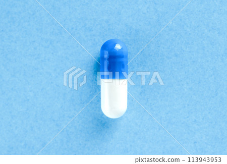White and blue pharmaceutical pill. Medical capsule. Tablet on blue background with copy space. Health concept. White and blue pharmaceutical pill. Medical capsule. Tablet on blue background with copy space. Health concept. 113943953