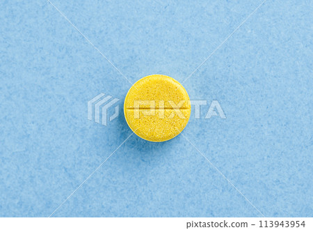 Single yellow pill tablet. Tablet on blue background with copy space. Health concept. Single yellow pill tablet. Tablet on blue background with copy space. Health concept. 113943954