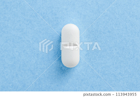 White medical pill tablet on blue. Tablet on blue background with copy space. Health concept. White medical pill tablet on blue. Tablet on blue background with copy space. Health concept. 113943955