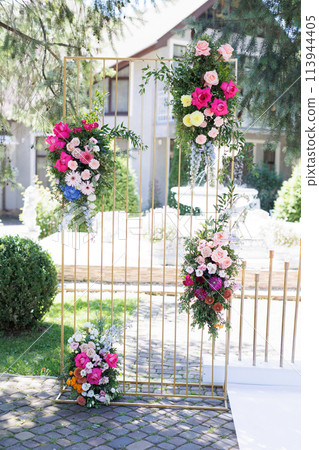 Beautiful bouquets of flowers hang on the wedding arch on the day of celebration Beautiful bouquets of flowers hang on the wedding arch on the day of celebration 113944405
