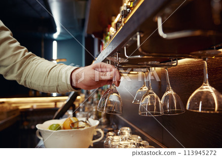 Closeup hand of bartender taking clean glass for cocktail Closeup hand of bartender taking clean glass for cocktail 113945272