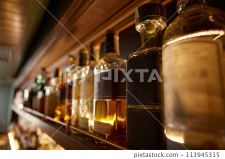 Bar counter with many bottles of alcoholic drinks assortment 113945315
