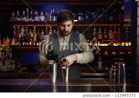 Confident bartender male pouting liquor to make cocktail 113945373