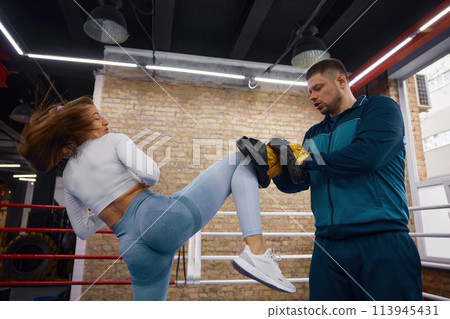 Active woman kickboxing with trainer at health gym club Active woman kickboxing with trainer at health gym club 113945431
