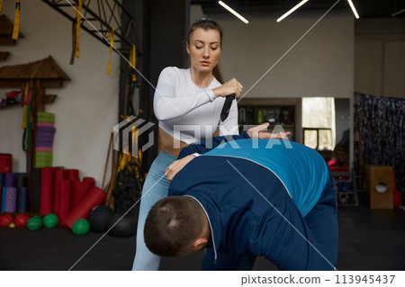 Young sportive woman exercising with knife weapon with trainer 113945437