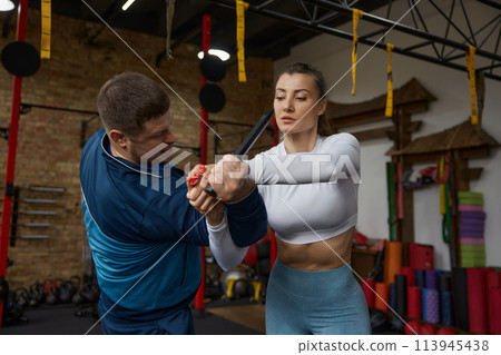 Young sportive woman exercising with knife weapon with trainer Young sportive woman exercising with knife weapon with trainer 113945438