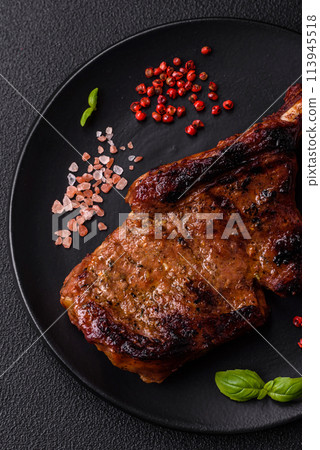 Delicious juicy beef steak on the bone, tomahawk with salt, spices and herbs Delicious juicy beef steak on the bone, tomahawk with salt, spices and herbs 113945518