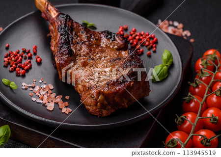 Delicious juicy beef steak on the bone, tomahawk with salt, spices and herbs Delicious juicy beef steak on the bone, tomahawk with salt, spices and herbs 113945519