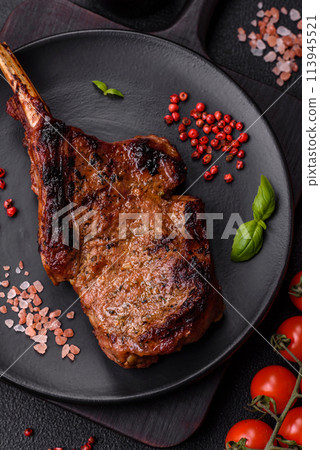Delicious juicy beef steak on the bone, tomahawk with salt, spices and herbs 113945521