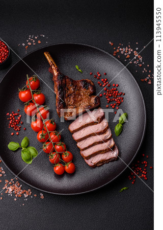 Delicious juicy beef steak on the bone, tomahawk with salt, spices and herbs Delicious juicy beef steak on the bone, tomahawk with salt, spices and herbs 113945550