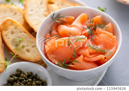 Making salmon and cream cheese bruschetta with dill and capers 113945626