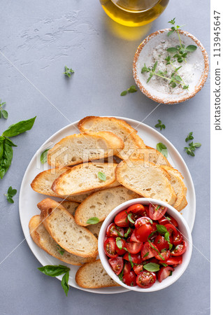 Making tomato basil bruschetta with toasted baguette and herbs Making tomato basil bruschetta with toasted baguette and herbs 113945647