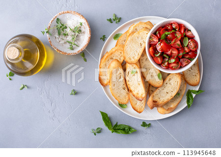 Making tomato basil bruschetta with toasted baguette and herbs Making tomato basil bruschetta with toasted baguette and herbs 113945648