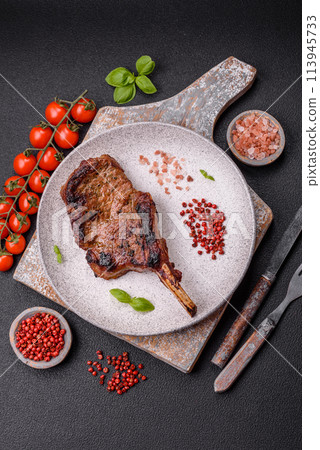 Delicious juicy beef steak on the bone, tomahawk with salt, spices and herbs Delicious juicy beef steak on the bone, tomahawk with salt, spices and herbs 113945733