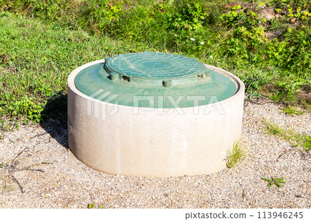 Sewer manhole of rural septic tank with green plastic cover, sewage system 113946245