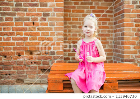 Child girl walks and have fun outdoor with cochlear implant on the head. Hearing aid and treatment concept. Inclusion and disability. 113946730