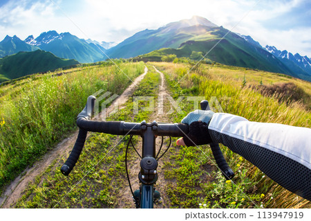 hands on the handlebars of a bicycle of a cyclist riding along a trail in nature. Point of view hands on the handlebars of a bicycle of a cyclist riding along a trail in nature. Point of view 113947919